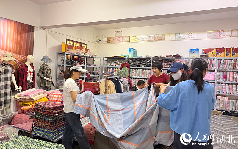 游客正在挑选红安大布床品。人民网记者 张隽摄