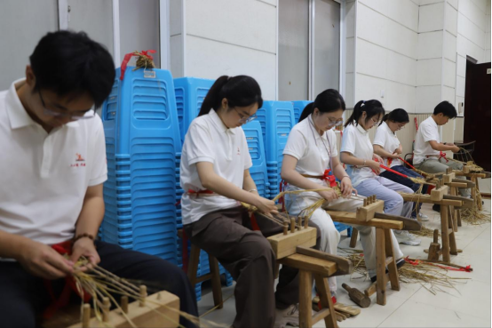 在红色民俗体验课堂上，实践团成员学习编织红军草鞋。学校供图
