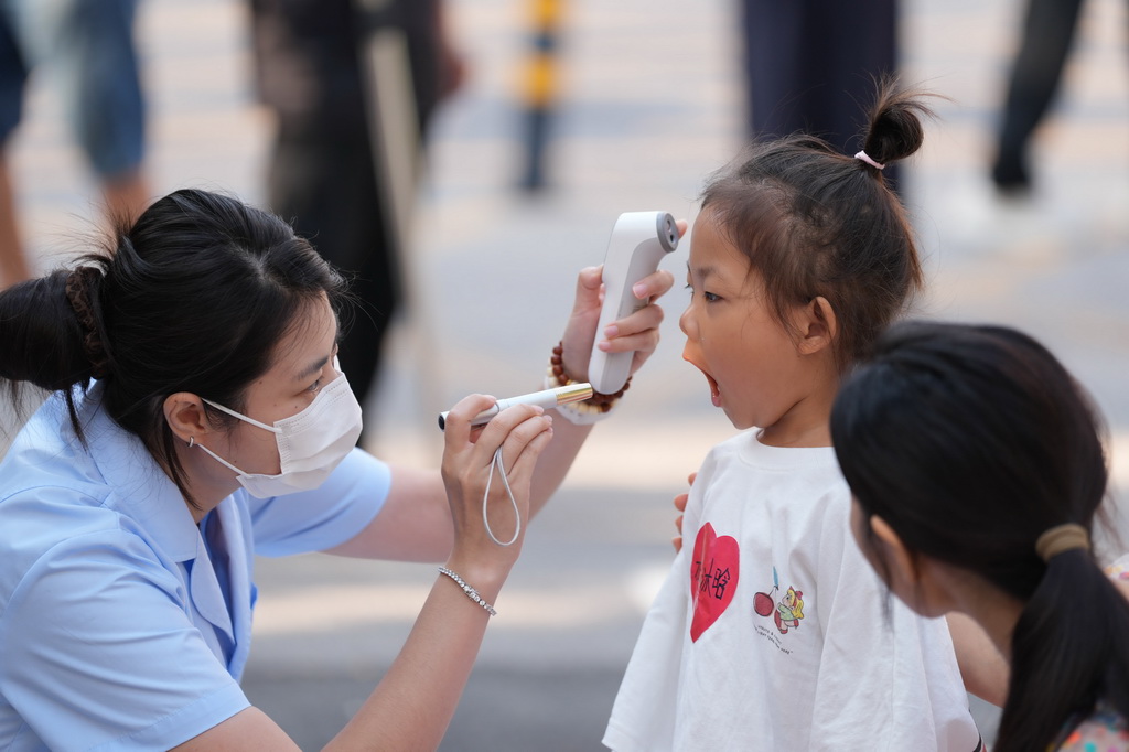 9月2日，北京九龙幼儿园的老师在给孩子做入园晨检。